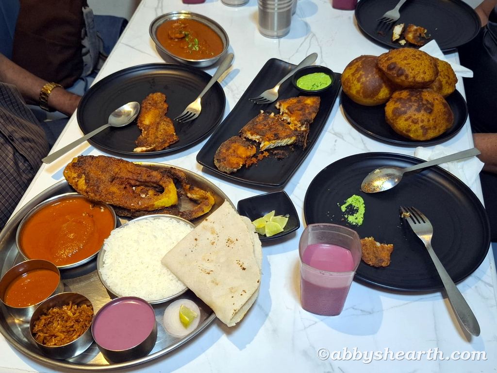 Table with rawas thali (king salmon plate), surmai fry (fried kingfish) and thisra (cockles) at Aplo Konkan.