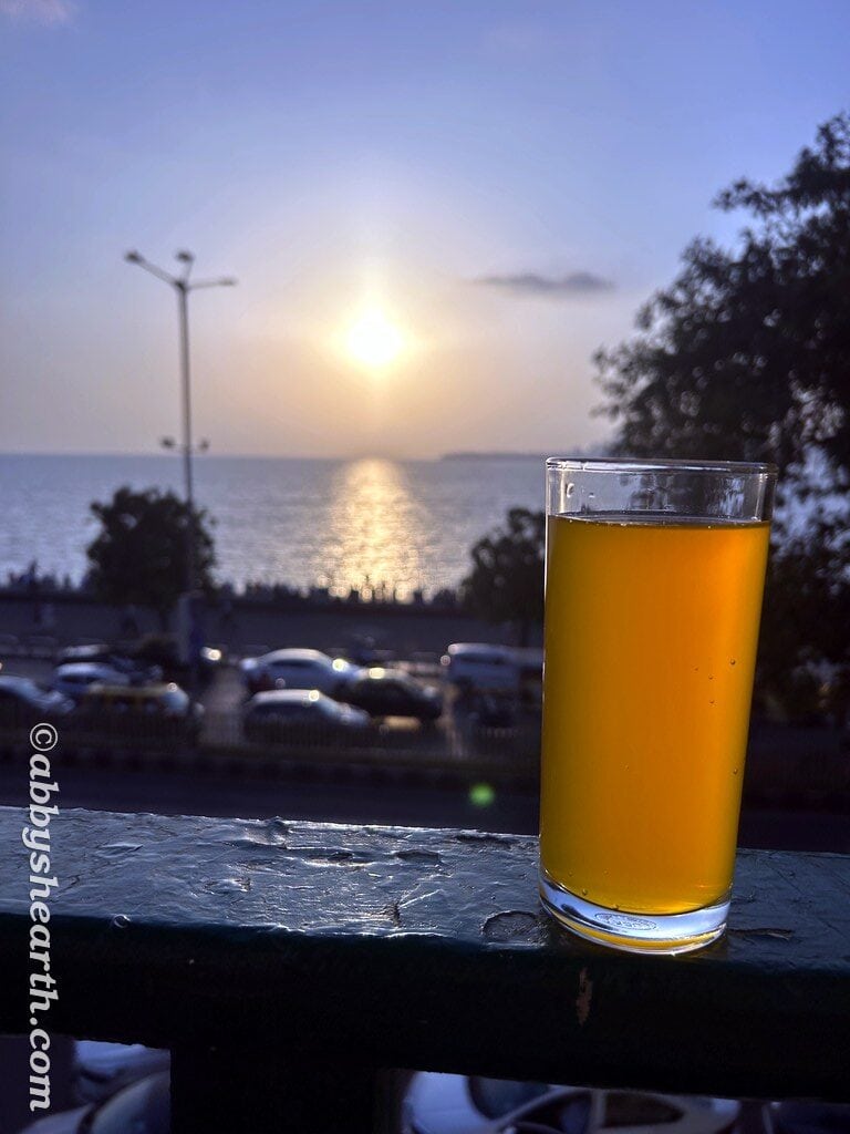 Scenic sunset view over Mumbai with a glass of beer in foreground.