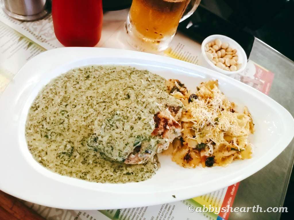 Dish with creamy green sauce, pasta, and side condiments on a white plate.