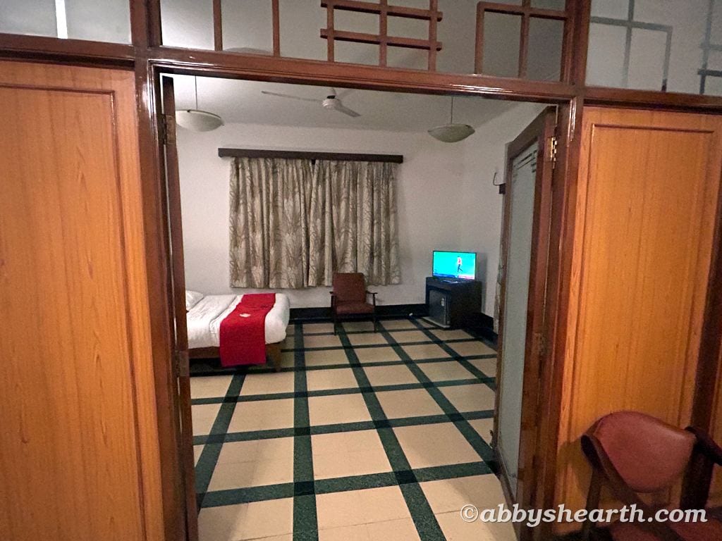 Interior of a hotel room with bed, TV, and window with curtains.