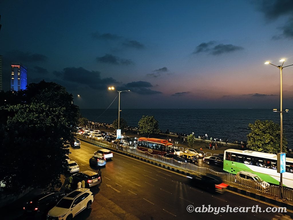 View of Marine Drive with cars and buses at sunset in Mumbai.