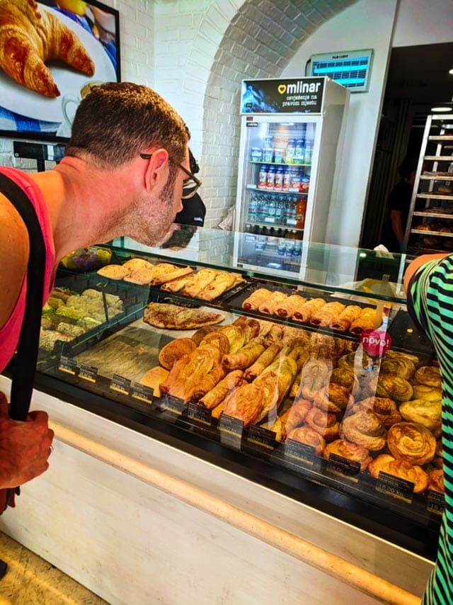 Man looking at meat pies in a pastry shop in Prague.
