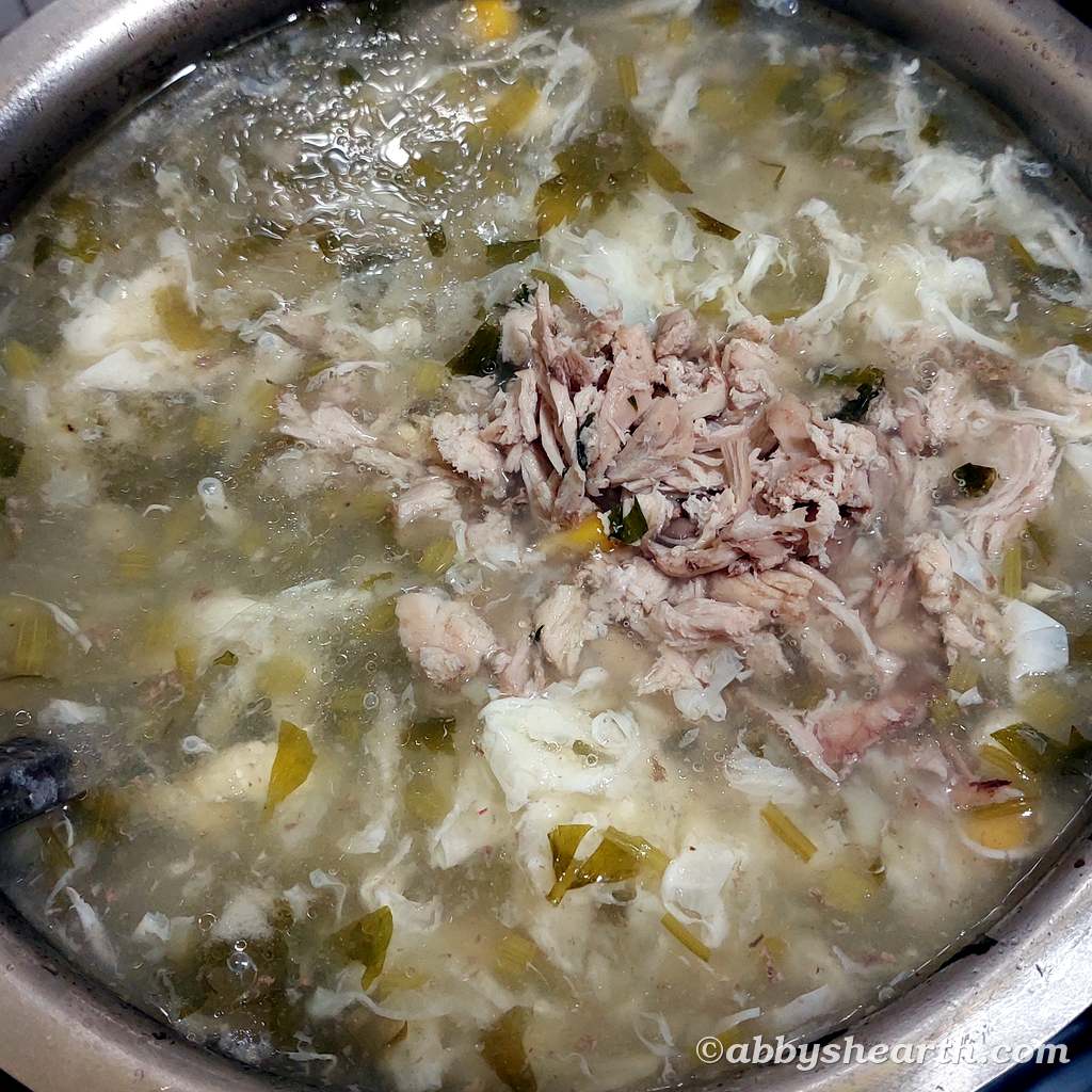 Adding shredded chicken to sweetcorn chicken and celery soup.
