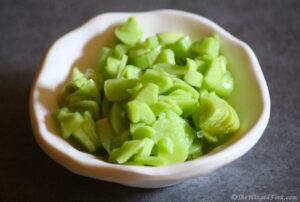 Pickled green garlic in a white bowl.