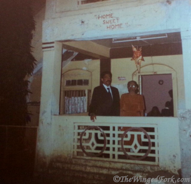 Man and older woman (mother) on the balcony of old East Indian bungalow.