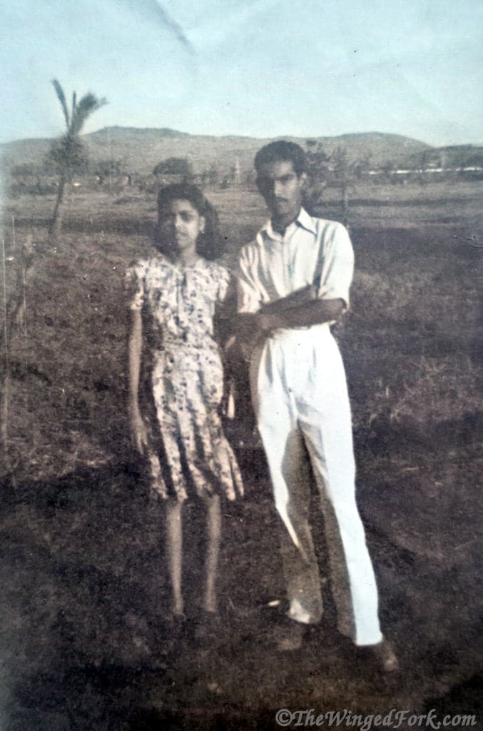 A young couple standing in front of some trees and mountains.