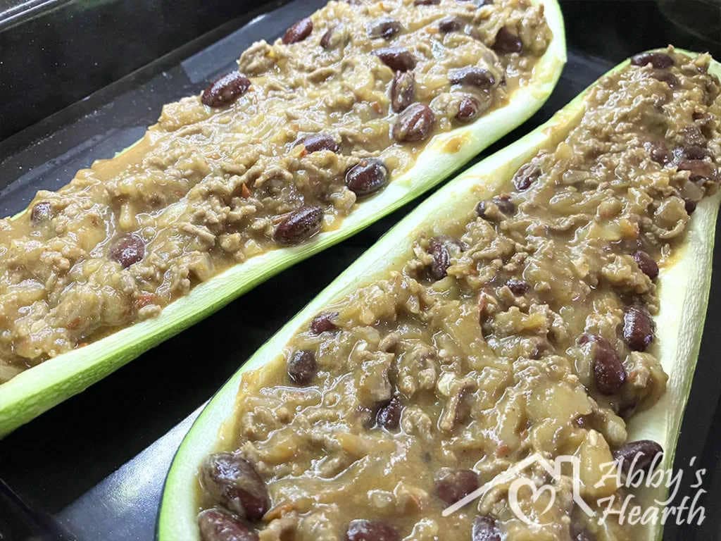 Two zucchini shells filled with beef mince and kidney beans, ready for the cheese topping.