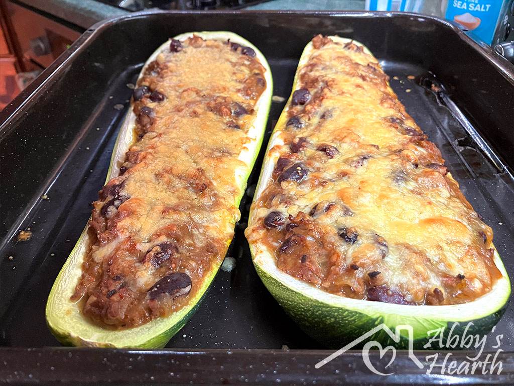Two baked zucchini boats filled with beef mince, kidney beans and golden melted cheese, fresh out of the oven.