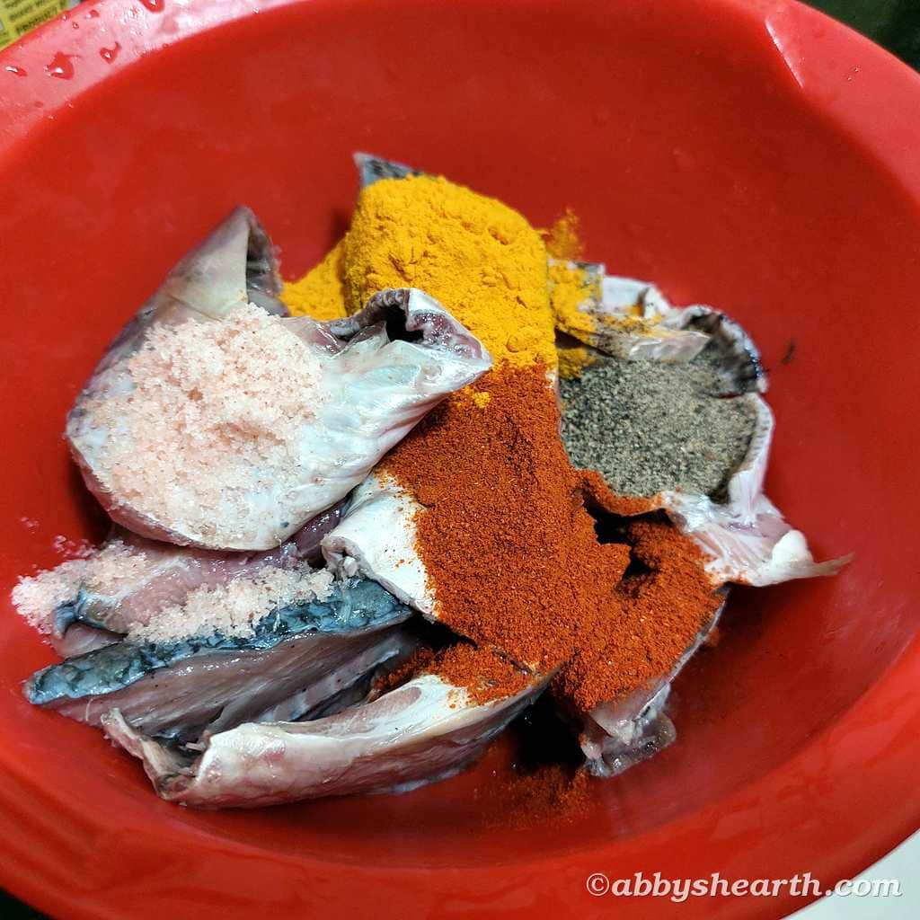 Mom adds salt, chili powder, turmeric powder, and pepper to the fish.