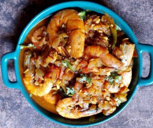 Atwan curry of prawns in a green flat dish.