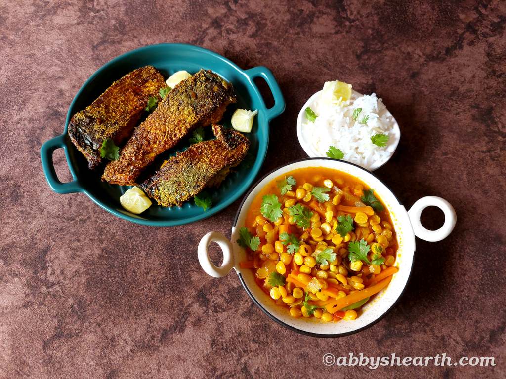 Fried palla fish next to rice and chana dal.