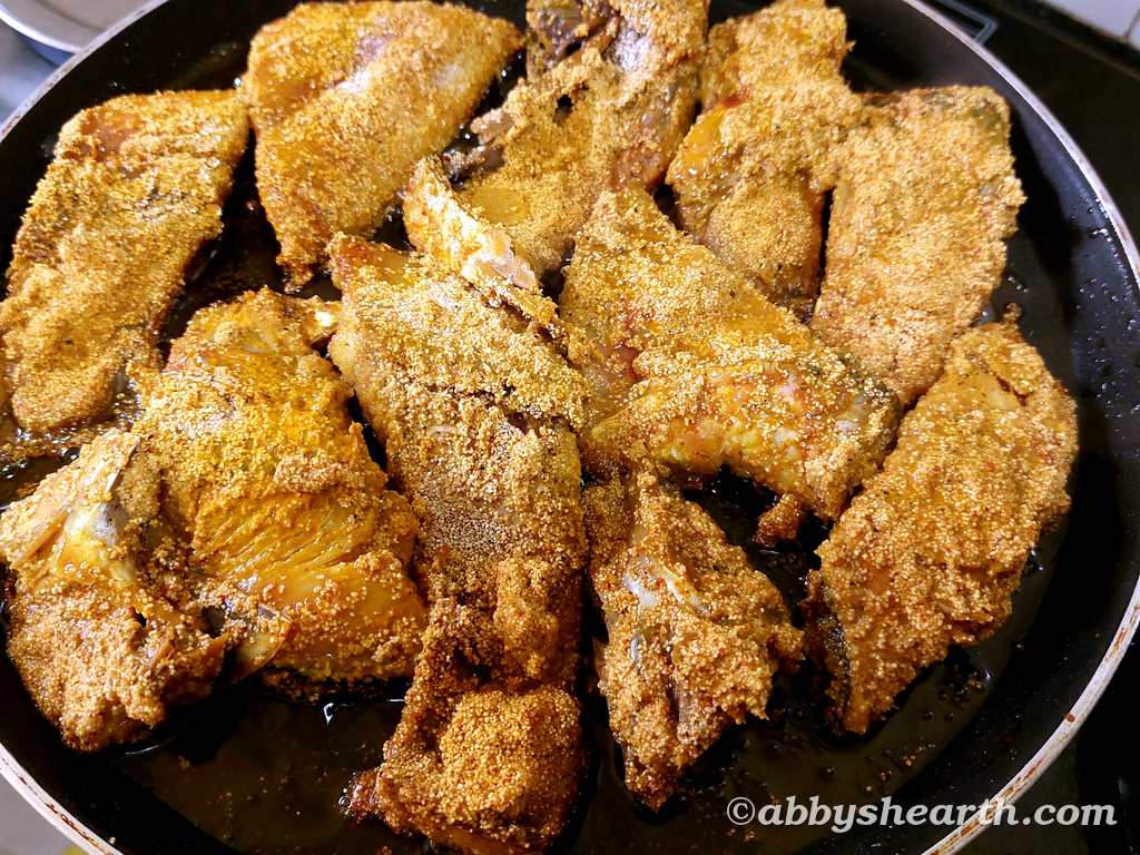 Palla/hilsa fish coated with semolina frying in a pan.
