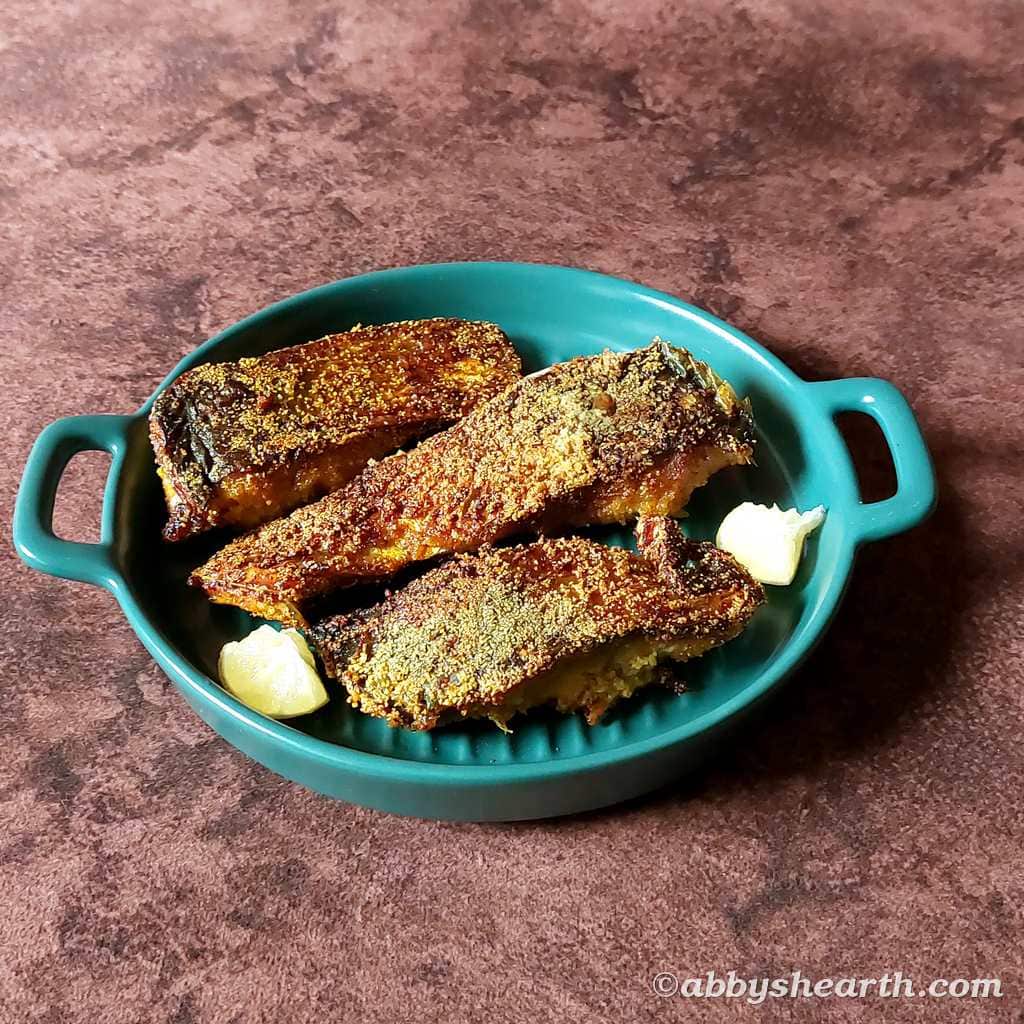 Semolina crusted fried palla in a green serving dish with lemon.