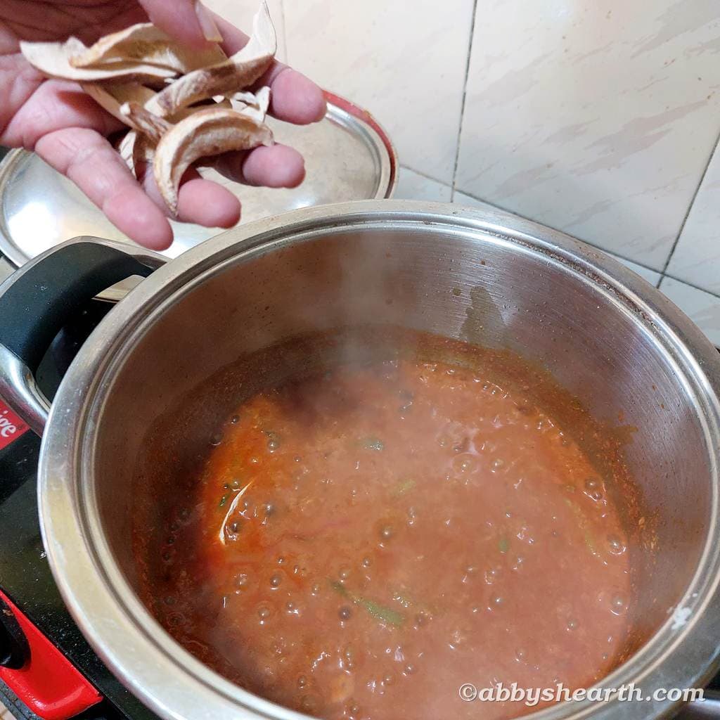Hand adding amoshi (sundried mango) to the curry.