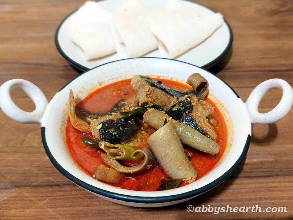 Pakat Lonvas curry in a pot next to a plate of apas/handbreads.