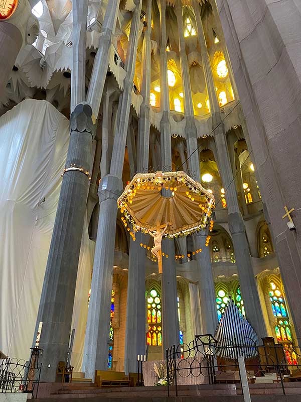 Suspended crucifix hangs beneath a canopy of wheat and grape.