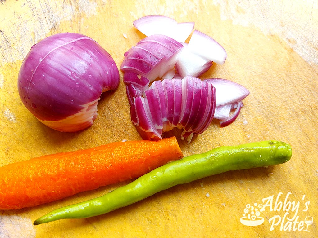 Onion, carrot and chili on a chopping board.