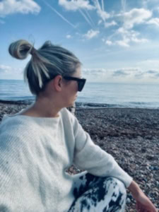 Blond lady facing the sea.