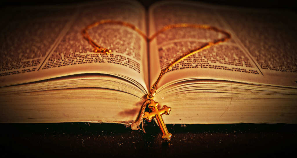 Gold chain with cross in a heart shape in a Bible.