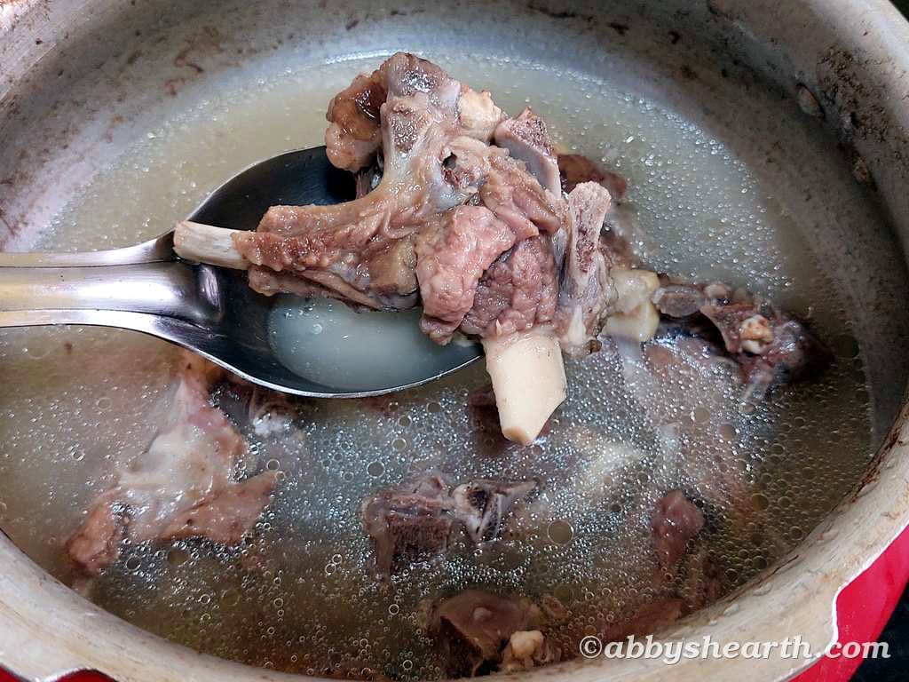 Cooked mutton chop on a spoon above the cooker.