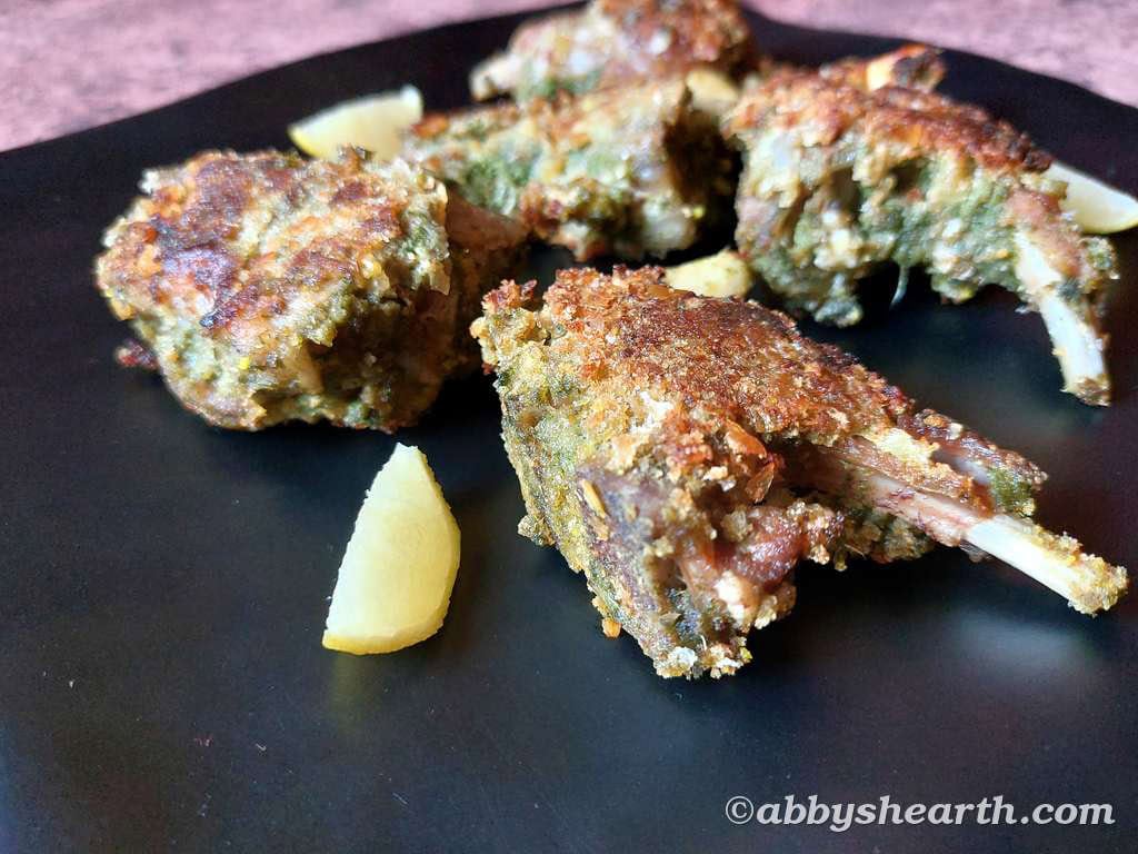 Mutton chops in a black platter with wedges of lemon.