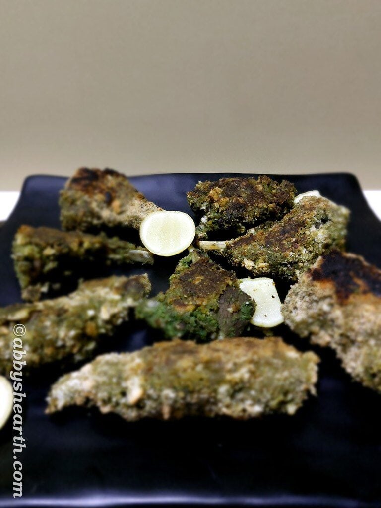 Mutton chops in a black platter with wedges of lime.