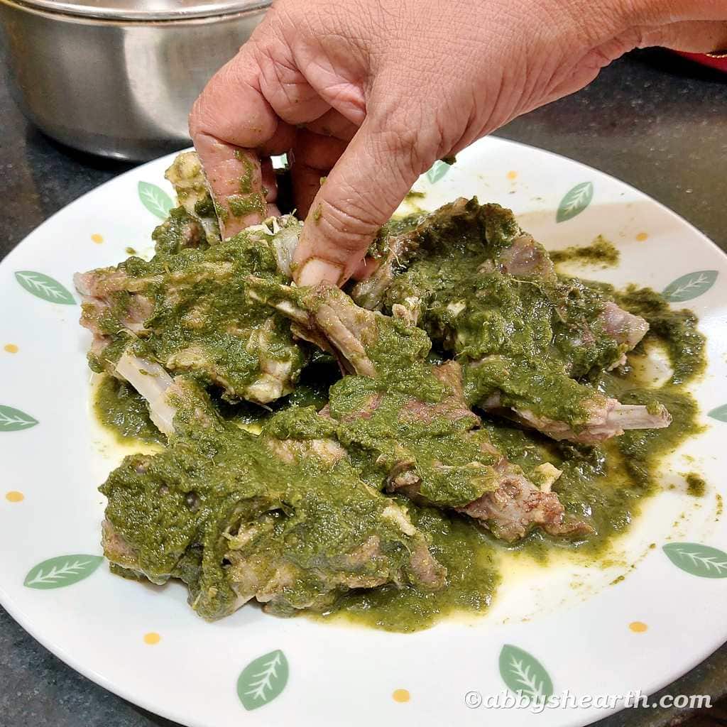 Mom coats the mutton chops with the green mix in a plate.