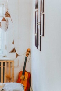 A wall with photo frames and a guitar in the corner.