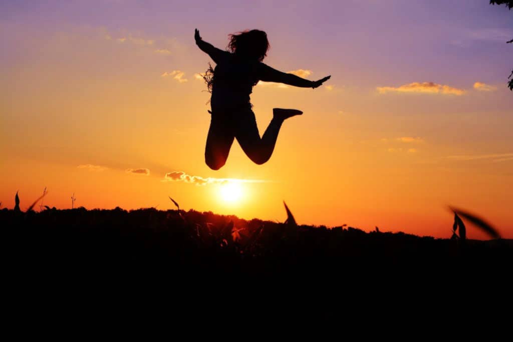 Woman jumping in front of the sunset.