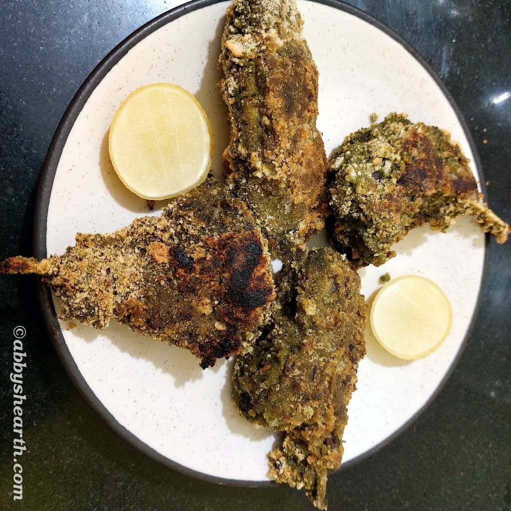 Four chunky goat rib chops on a plate with wedges of lime.