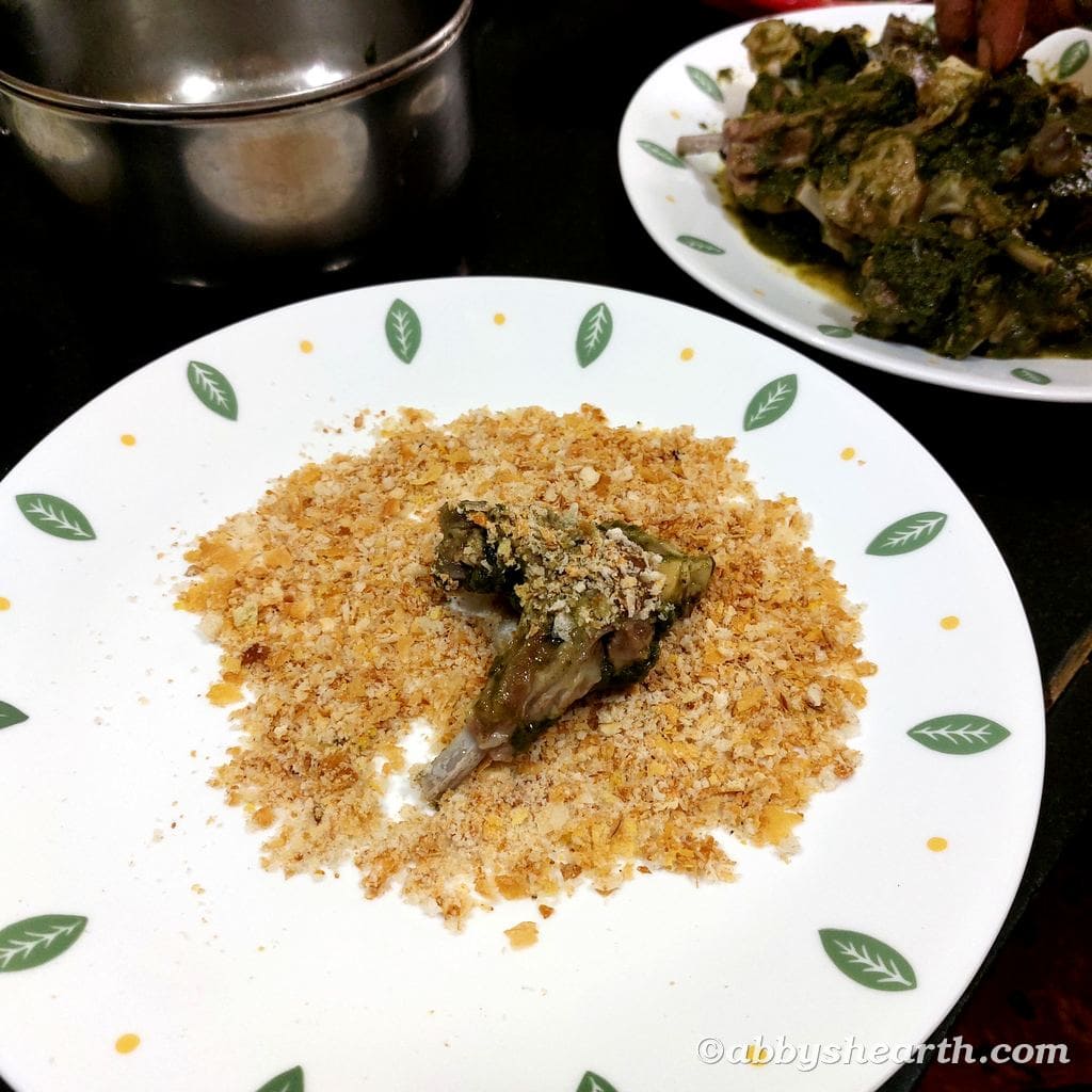 Chutney coated mutton chop in a plate of crumbs.