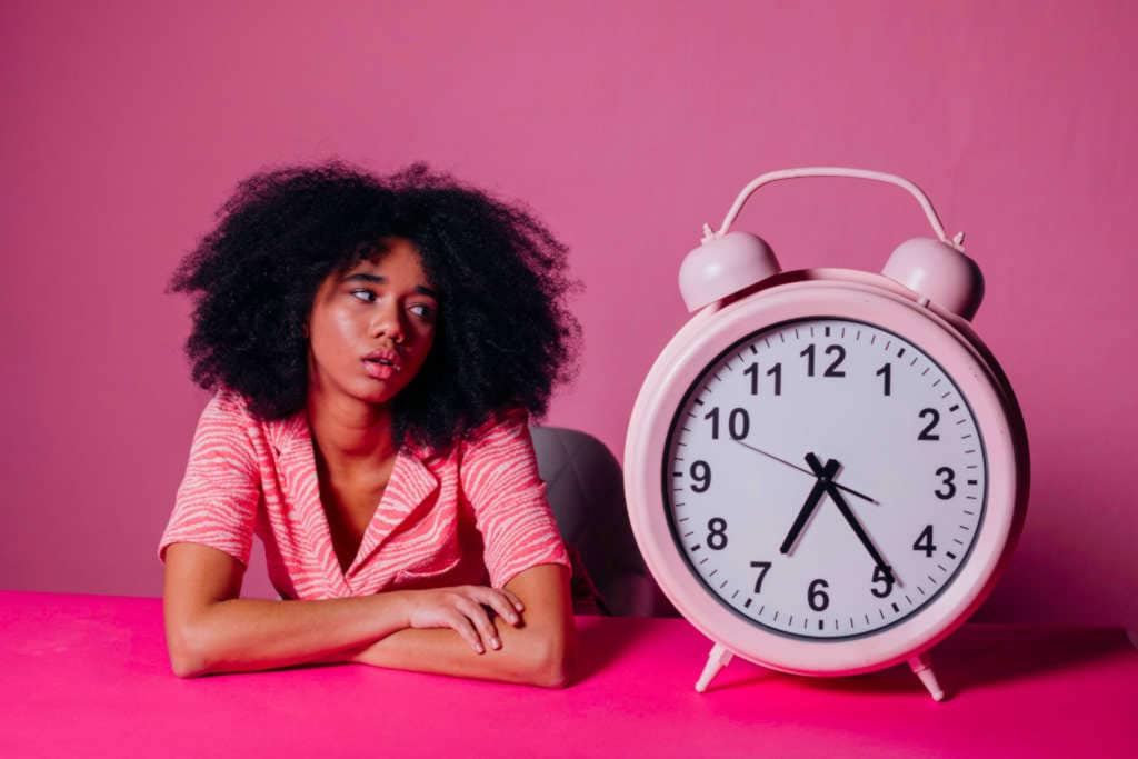 Disappointed or tired woman looking at an alarm clock.