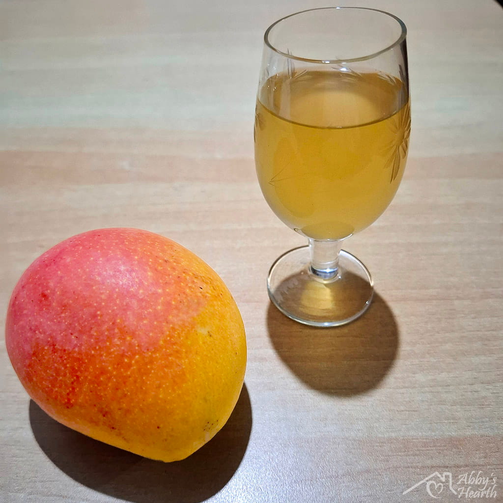 Mango and glass of mango wine placed on the table.
