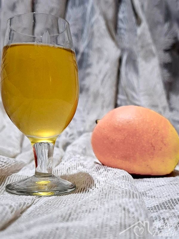 Glass of mango wine and mango placed on a cloth.