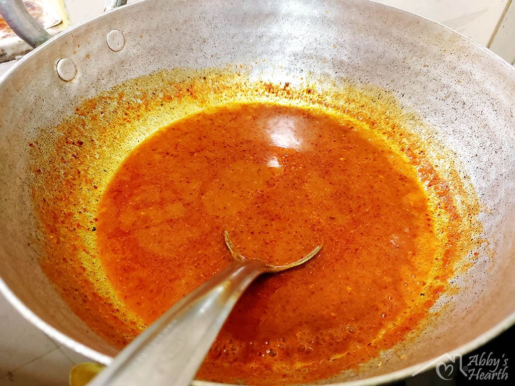 Red masala gravy is getting cooked in the kadhai.
