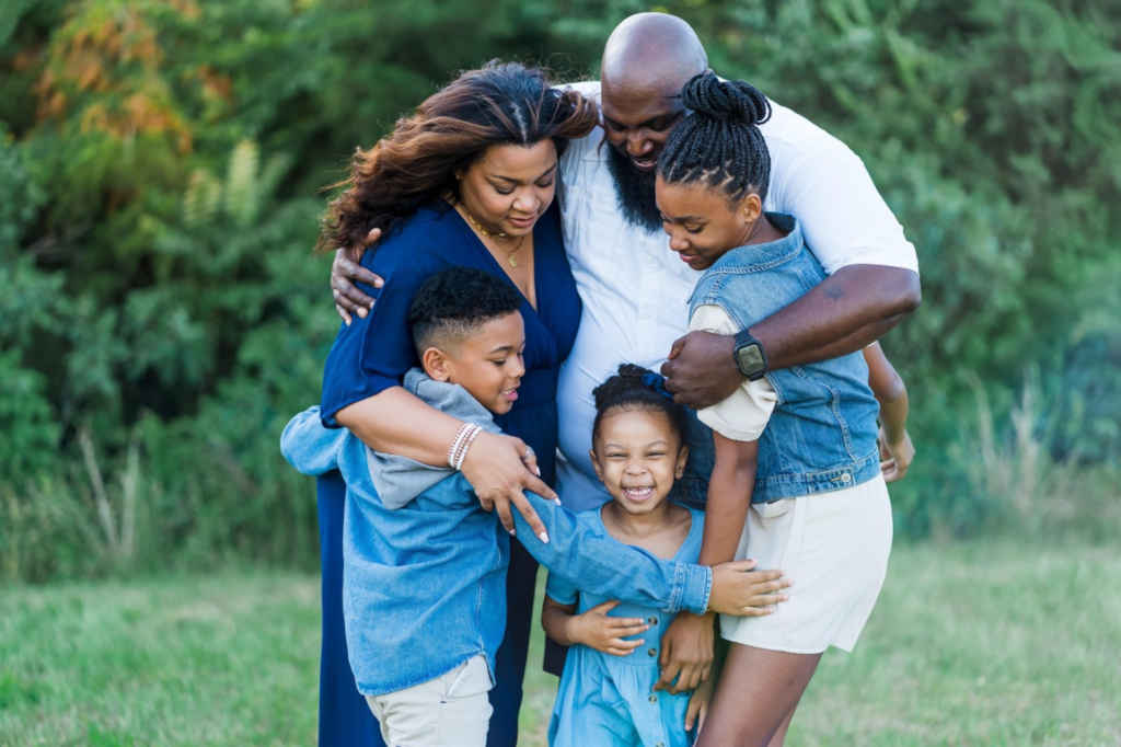 A family of five dressed in blue and white hugging each other.