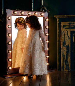 Girl dressed like princess looking in a mirror.