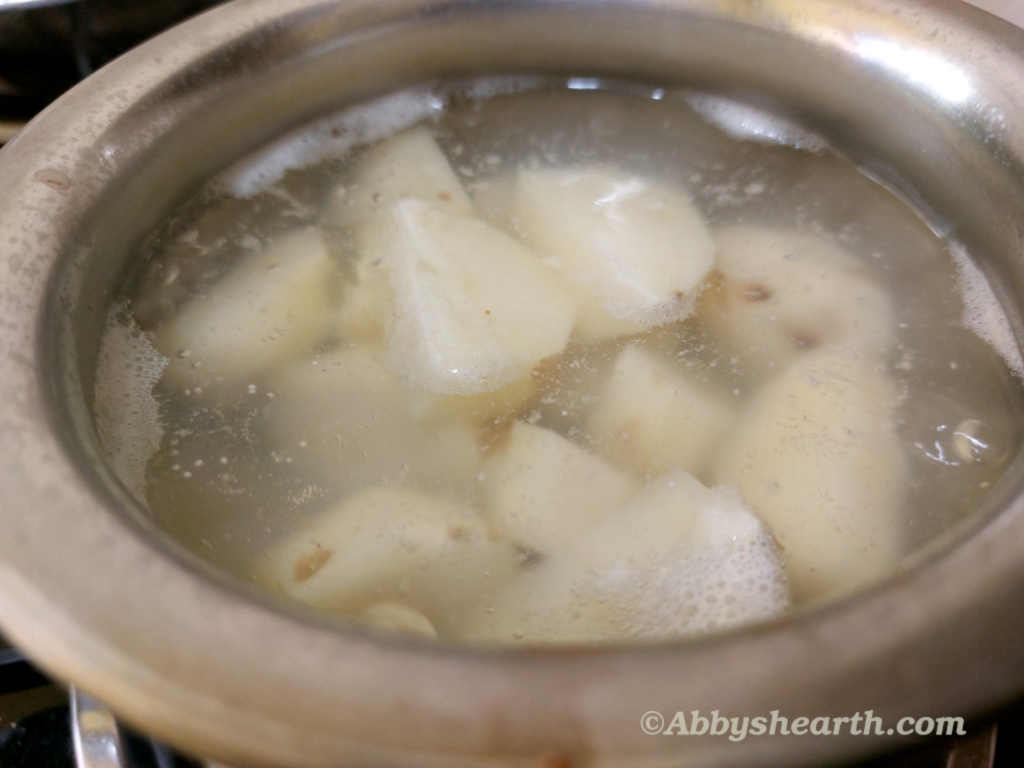 Potatoes cut in quarters boiling in another pot.