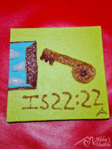 Key and door with Isaiah 2222 written on iton yellow canvas.