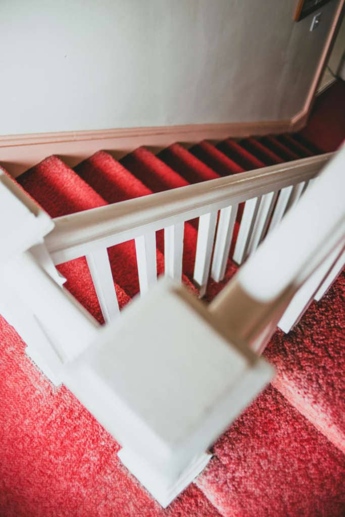 White staircase with red carpeted stairs and surrounnding.