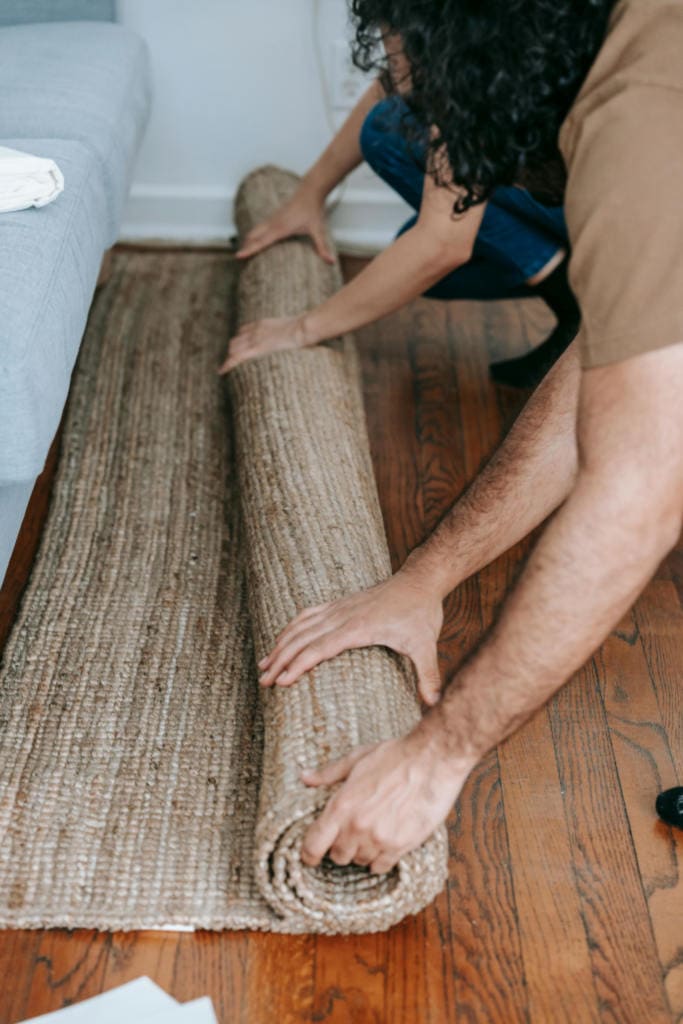 Two people rolling up a carpet.