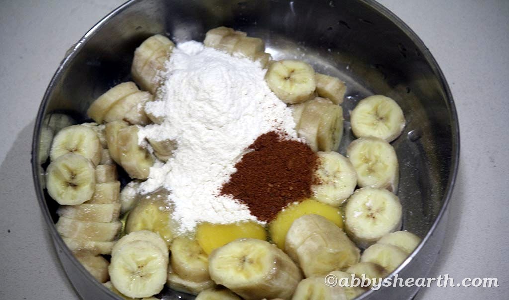 Sliced overripe bananas and two eggs in a steel mixing bowl.