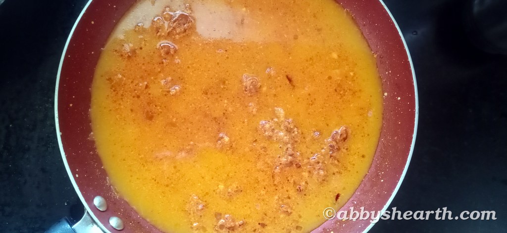 Red masala cooking in a frying pan.