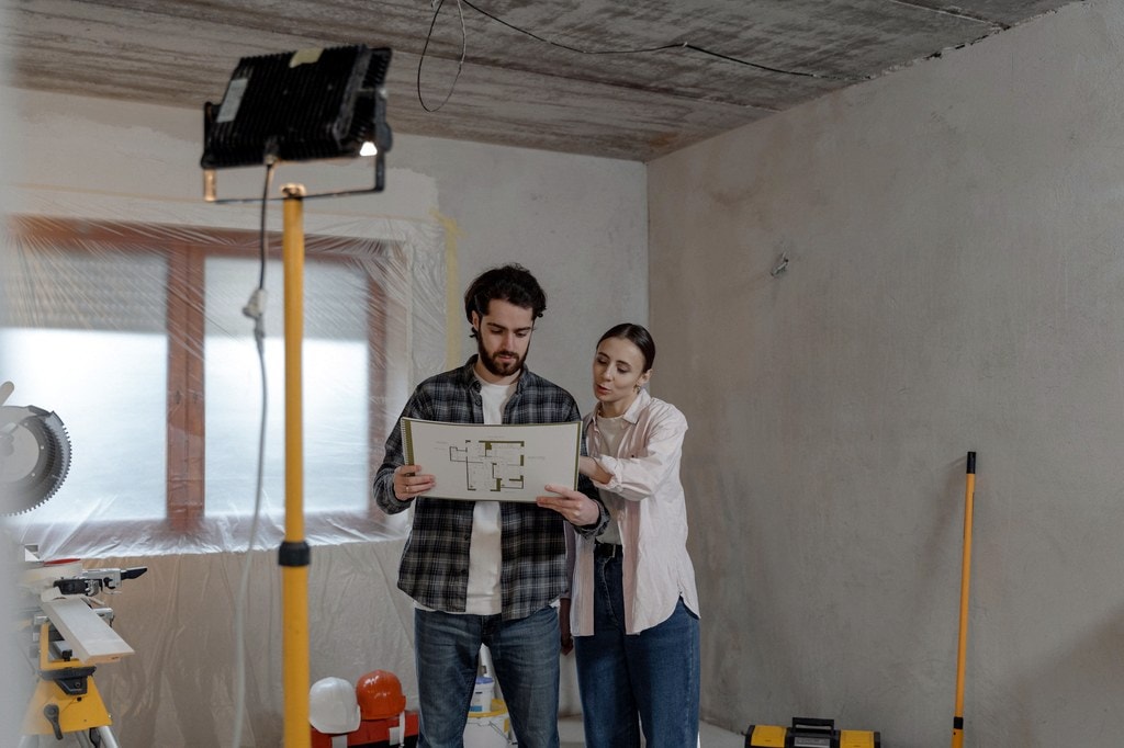Couple reading floor plan in a home being refurbished.