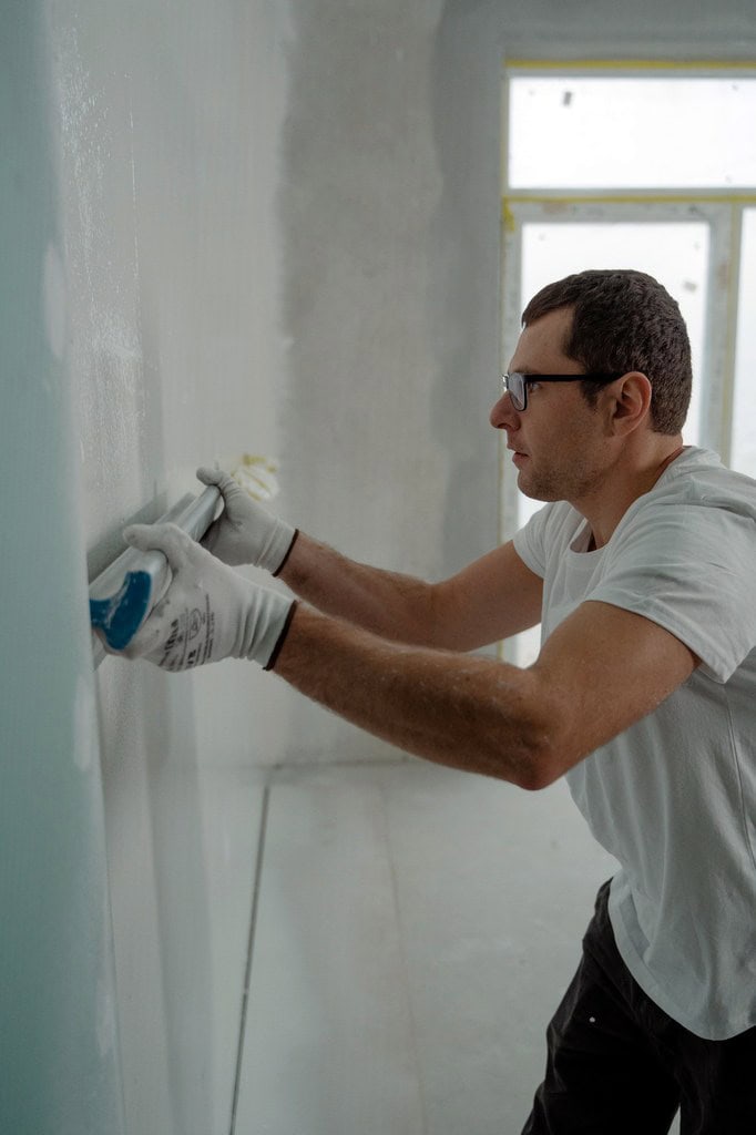 Man smoothening wall paint.