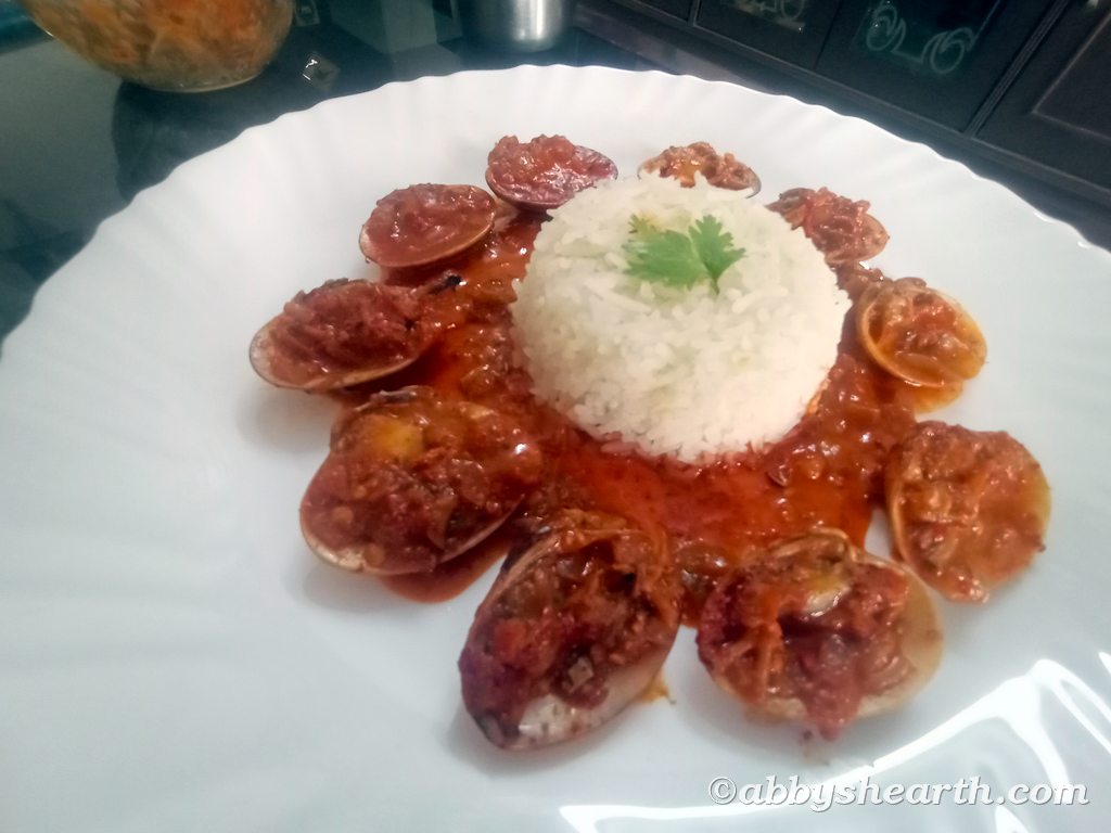 Cockle curry in a plate with white rice.