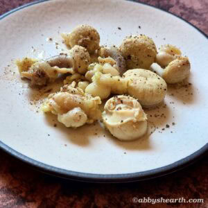 Coarse ground pepper on boiled goat testicle slices in a plate.