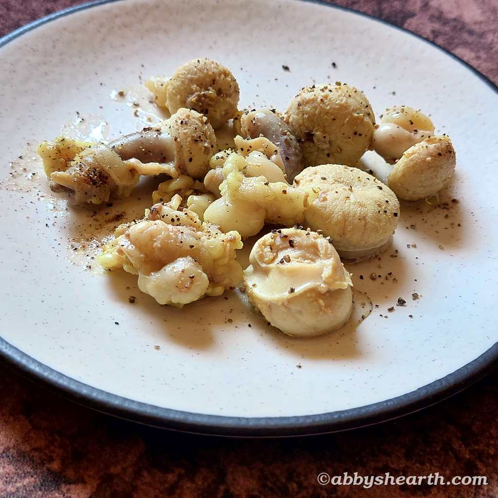 Coarse ground pepper on boiled goat testicle slices in a plate.