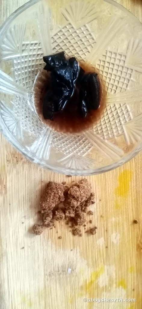 Kokum soaking in water in a bowl next to jaggery powder.