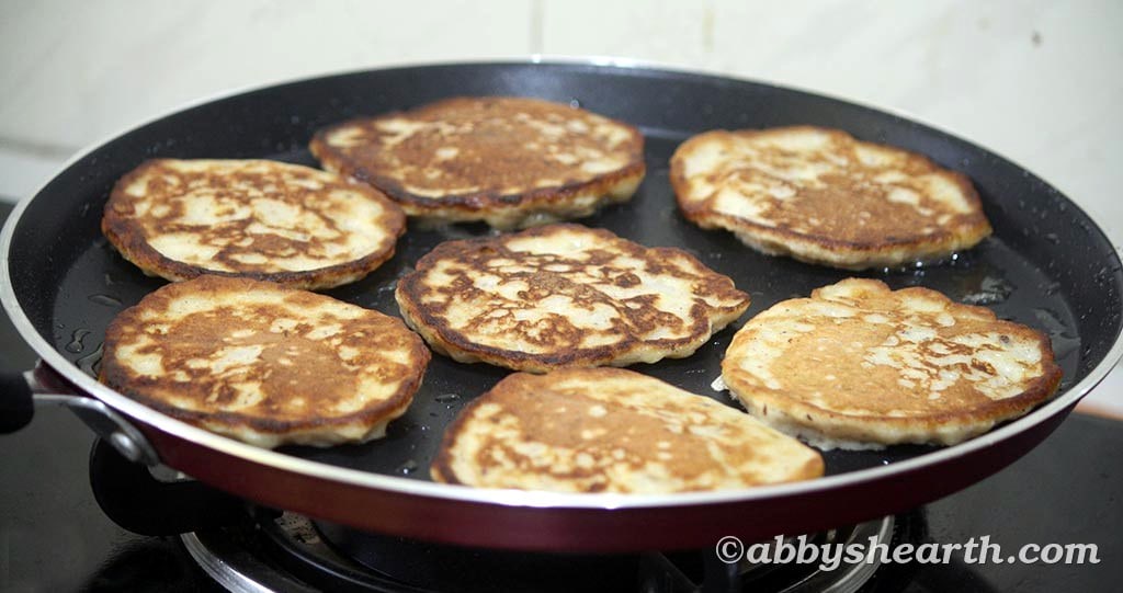 Sugar-free banana fritters flipped in a frying pan, golden brown.